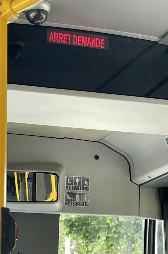 Das Bild zeigt das leuchtende "Stop"-Schild im Fahrzeug auf Französisch, also "Arret demande"